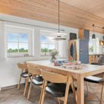 Essbereich mit Holztisch, Stühlen und Küchenbereich im Hintergrund.