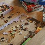 Puzzlestücke auf Holztisch. Mehrere Puzzles in verschiedenen Schwierigkeitsgraden.