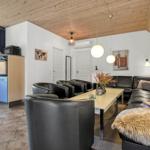 Wohnbereich mit Leder-Sofa, Esstisch und Küchenzeile unter Holzdecke.
