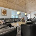 Wohnzimmer mit Ledersofa, Tisch und Sesseln. Holzdecke und Fenster sichtbar.