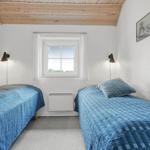 Zwei Betten mit blauen Bettdecken, Fenster und Decke aus Holz.