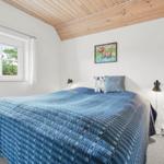 Schlafzimmer mit Bett, Fenster und Holzdecke.