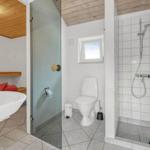 Bad mit Dusche, Toilette und Waschbecken. Holzdecke und Fenster sichtbar.