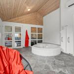 Rundes Whirlpoolbad mit Holzdecke und Glaswänden. Rote Bademäntel und Fliesenboden.