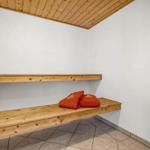 Sauna mit Holzbank und orangefarbenen Handtüchern an der Wand.