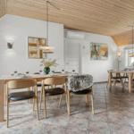 Esszimmer mit Holztisch, Stühlen und Kaminofen. Holzdecke und Wandgemälde.