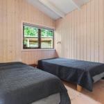 Two beds with dark covers in a room with wooden walls and a window.