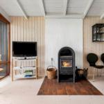 Living room with fireplace, TV, and seating. Wooden walls and terrace door.