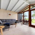 A living room with a gray sofa, wooden floor, and large windows to the terrace.