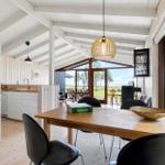 Dining area with table and chairs. Kitchen and terrace with view of green field.