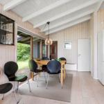 Dining room with wooden walls, table, chairs, and glass door to garden.