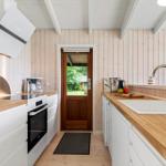 Kitchen with wooden surfaces, white cabinets, and view of garden