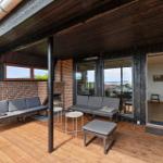 Terrasse mit Sitzgelegenheiten und Blick aufs Meer. Durchgang ins Haus.