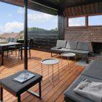 Terrasse mit Sitzgelegenheiten, Grillplatz und Blick auf Wasser.