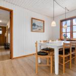 Esszimmer mit Tisch, Stühlen und Fenster. Durchgang zum Flur mit Holztür.