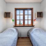 Zwei Betten unter einem Fenster mit Blick aufs Meer. Holzwände und -boden.
