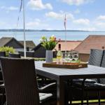 Terrasse mit Tisch, Stühlen und Blumen. Blick auf Wasser und Häuser.