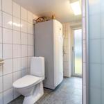 Bad mit Toilette, Duschbereich und Heizungsgerät an der Wand.