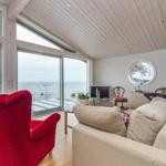 Wohnzimmer mit Blick aufs Meer, roter Sessel, Sofa und runde Fenster.