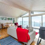 Wohnung mit Küchenbereich, Sofa und Meerblick durch große Fenster.