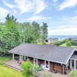House with wooden deck and garden, view of lake and trees.