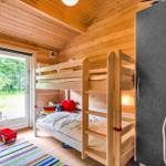 A bedroom with bunk bed, wooden walls, and door to the garden.
