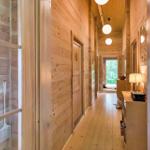 Wood-paneled hallway with lamp and door. Corridor leading to outdoor area.