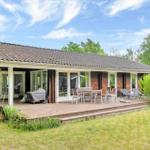 House with terrace, table, chairs, and loungers. Surrounded by green. Blue sky with clouds.