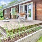 Deck with table and chairs in front of a wooden house with raised garden beds.