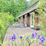 Wooden terrace with lounge chairs and flowers in front of a wooden house.