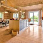 Kitchen and dining area with wooden floor, ceiling, and walls. Windows and glass door lead to the terrace.