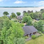 House with terrace and view of water and forest.
