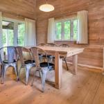Dining room with wooden walls, table, and metal chairs. Windows and glass door show greenery.