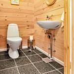 Bathroom with toilet, sink, and wood paneling.