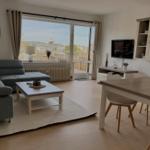 Wohn- und Essbereich mit Balkon, Sofa, Esstisch und Fernseher.