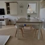 Essbereich mit Tisch und Stühlen, Fernseher und Schrank an der Wand.