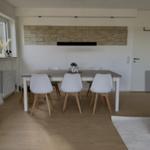 Esszimmer mit Tisch, Stühlen und Steinwand im Hintergrund.