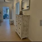 Flur mit Schrank und Spiegel. Im Hintergrund ist das Wohnzimmer mit blauem Sofa sichtbar.