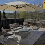 Terrasse mit Sitzgruppe, Sonnenschirm und Blick auf Wald.