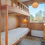 Ein Schlafzimmer mit Holzbett, Fenster und Schreibtisch.