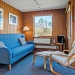 Ein Wohnzimmer mit blauem Sofa, Holzvertäfelung und Fensterblick auf Bäume.