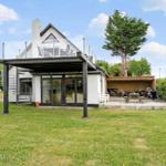 Moderne Villa mit Terrasse, Grillplatz und Garten. Glasdach und Holzveranda sichtbar.
