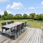 Terrasse mit Tisch und Stühlen, Blick auf grünen Garten und Häuser im Hintergrund.