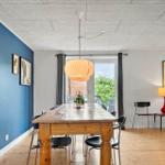 Esszimmer mit Holztisch, blauer Wand und Fenster zur Terrasse.