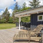 Deck with lounge chairs, table and chairs next to a house with dark siding.