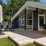 Modern villa with terrace, grill, and outdoor table. Surrounded by trees and grass.