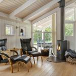 Two black leather armchairs with wooden legs are positioned in front of a wood-burning stove.
