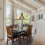 Dining area with wooden chairs, glass top, and large windows to the outside.