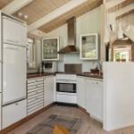 Kitchen with white cabinets, fridge, stove, and sink. Wooden ceiling and floor.