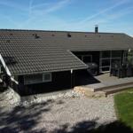Ein Haus mit Terrasse, Grill und Blick auf das Meer.